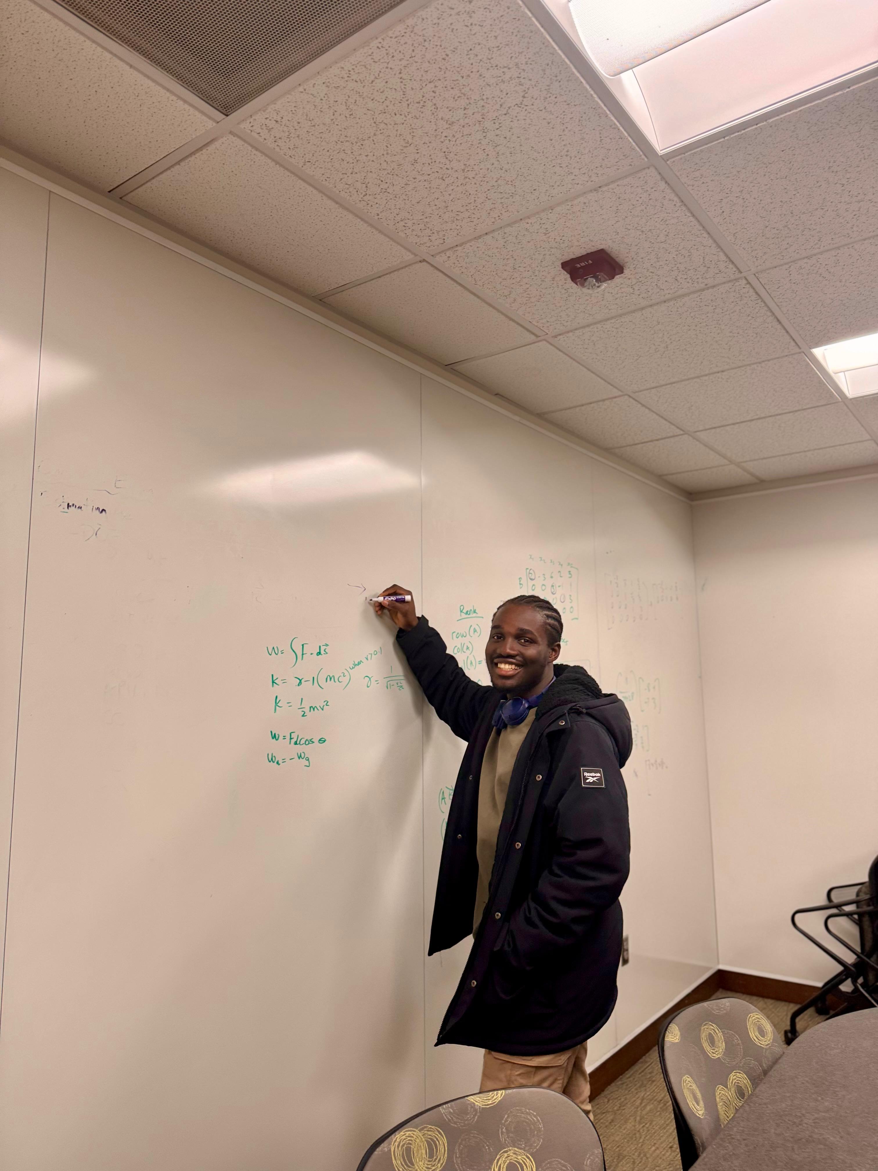 Calvin Andoh working through equations at a whiteboard