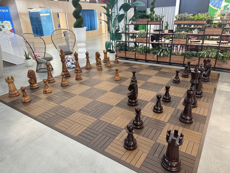 An oversized chess set mid-game on a wooden board